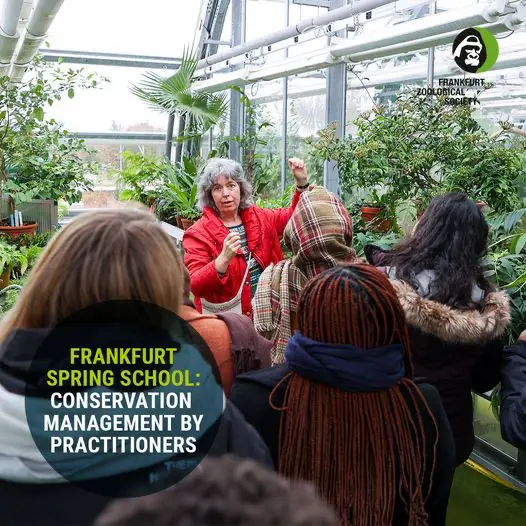 Eine Dozentin spricht vor einer Gruppe junger Menschen in einem Gewächshaus voller Pflanzen – Veranstaltung im Rahmen der ‚Frankfurt Spring School on Conservation Project Management‘, organisiert von der Zoologischen Gesellschaft Frankfurt.